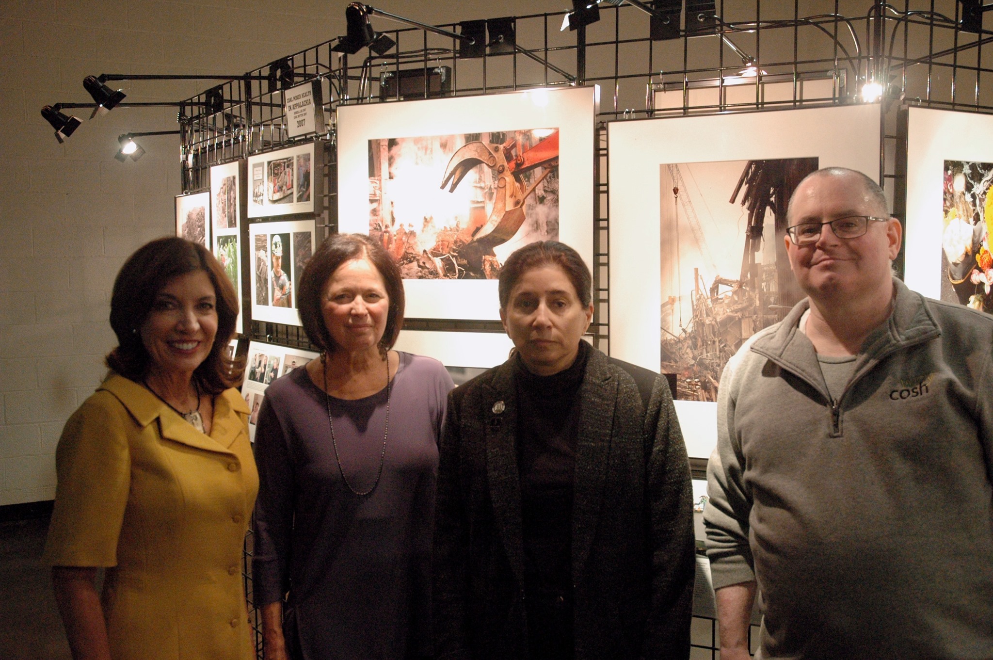 Four people pose in front of a photo exhibit
