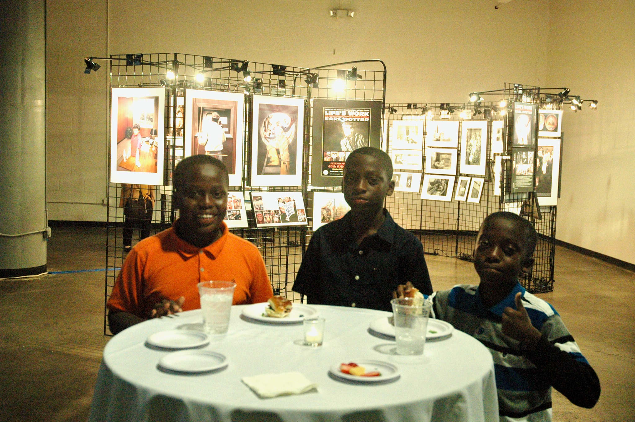 Three children in front of a photo exhibit